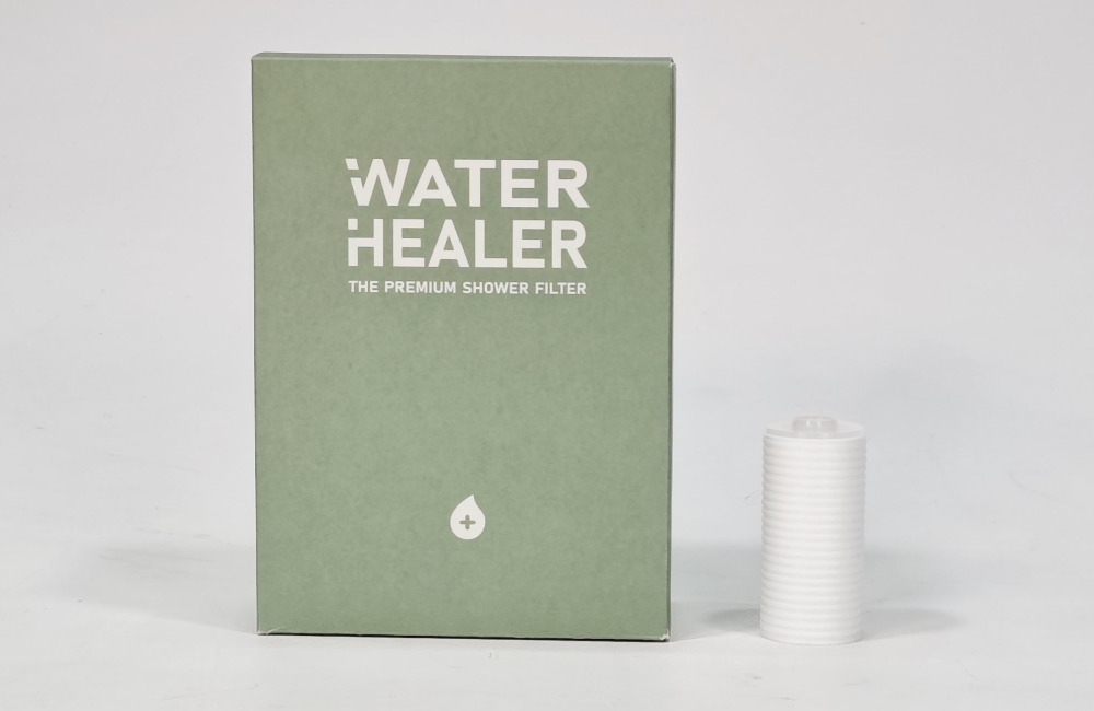 Replacement cartridge for a Water Healer travel shower filter beside its box